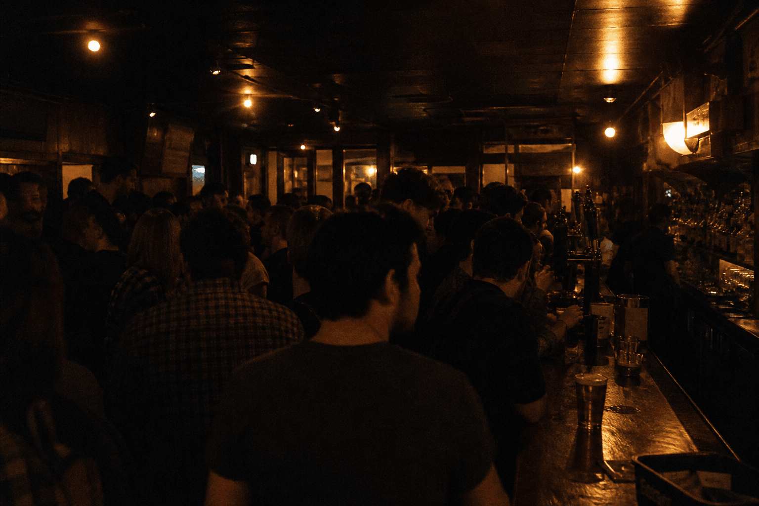 Packed bar floor at night, dim and cropped.